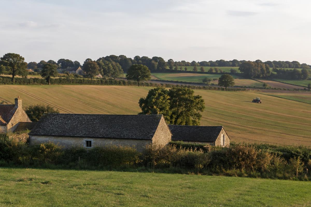 Oxfordshire farmland with stone barns and a tractor working an arable field